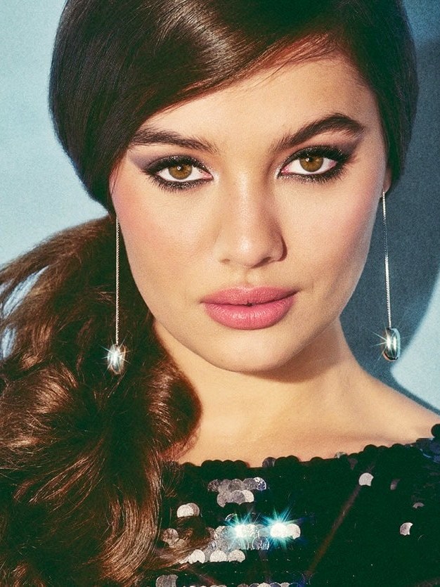 Model wearing dramatic eye makeup in a black embellished top