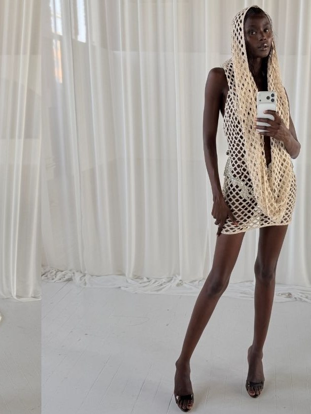 Model reclining outdoors in a sequined top and open-knit coverup, photographed in black and white