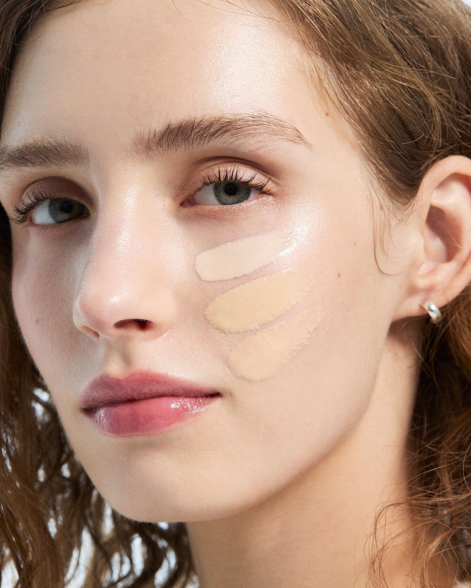 Close-up of a woman with three foundation swatches on her cheek