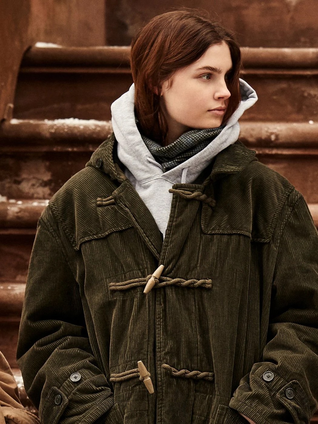 Model in a dark corduroy coat and layered sweatshirt in the Denimist Fall Winter campaign