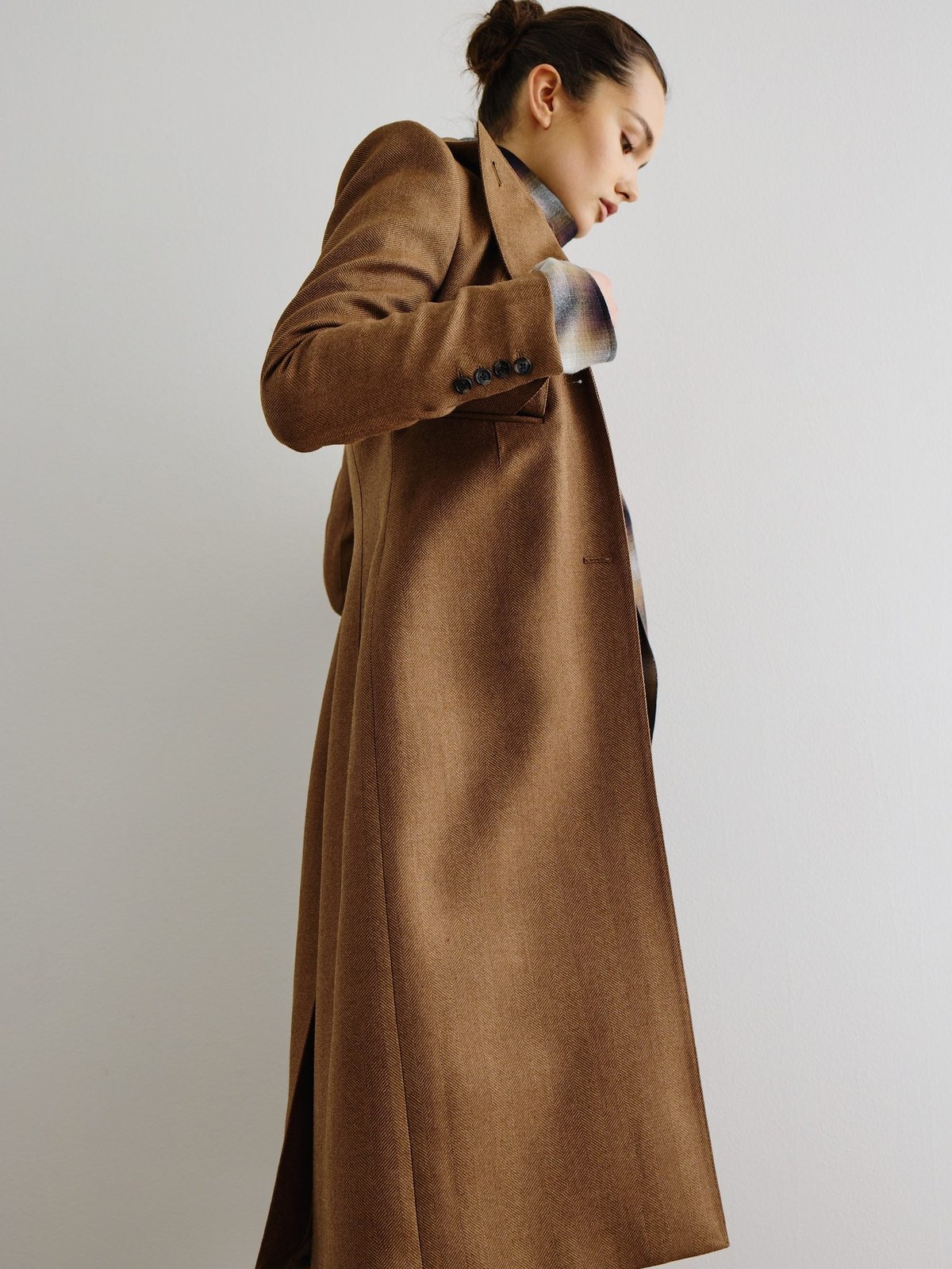 Model in a long camel Smythe coat against a simple studio backdrop