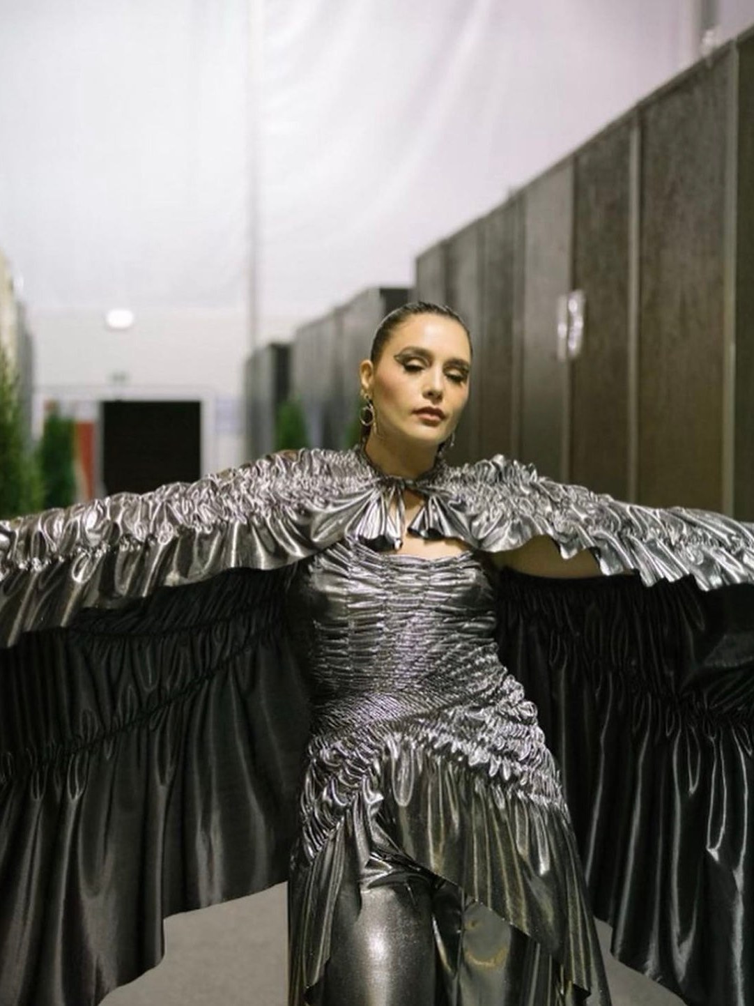 Jessie Ware in a silver sculptural dress with wide sleeves