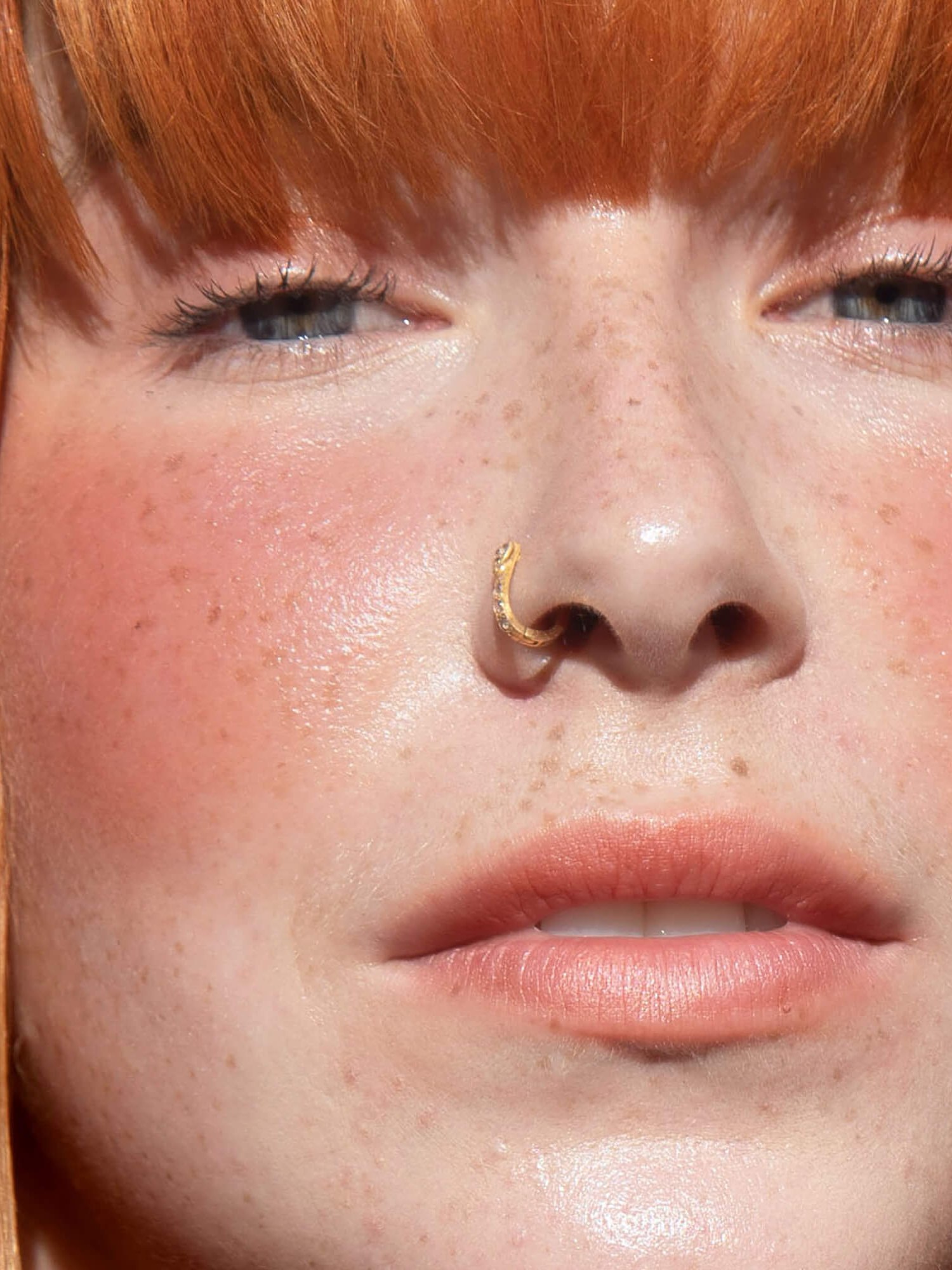 Close up of a freckled woman with red fringe and peachy blush
