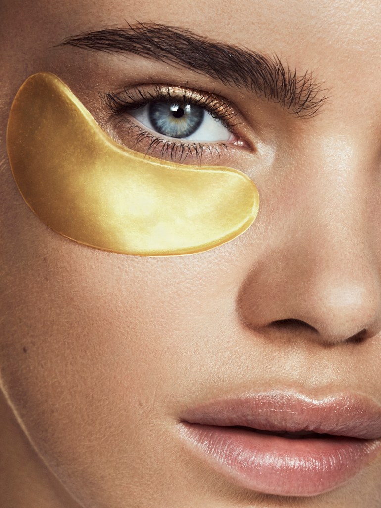Close beauty portrait of a model wearing a gold eye treatment patch