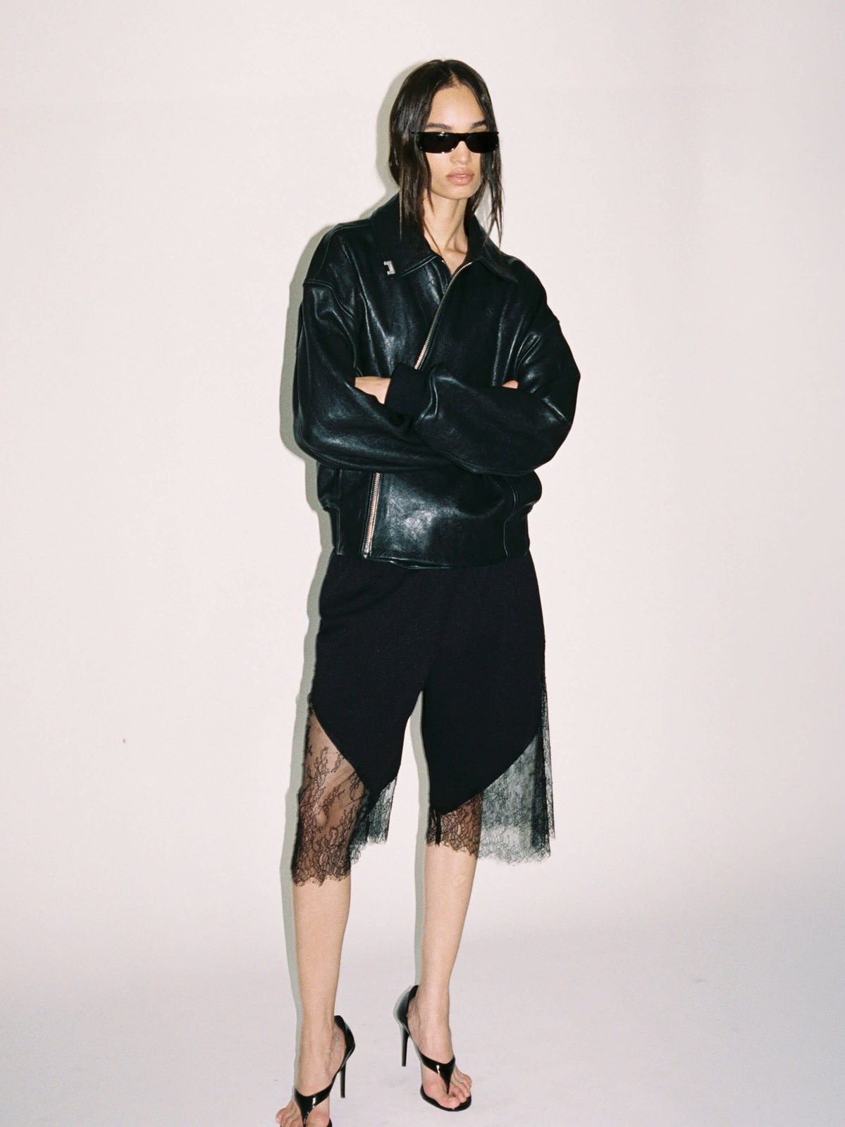 Model in a black leather jacket and lace skirt with dark sunglasses