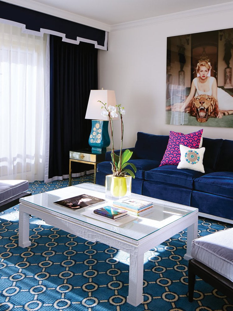 Blue and white living room with patterned rug, navy sofa and colorful accents
