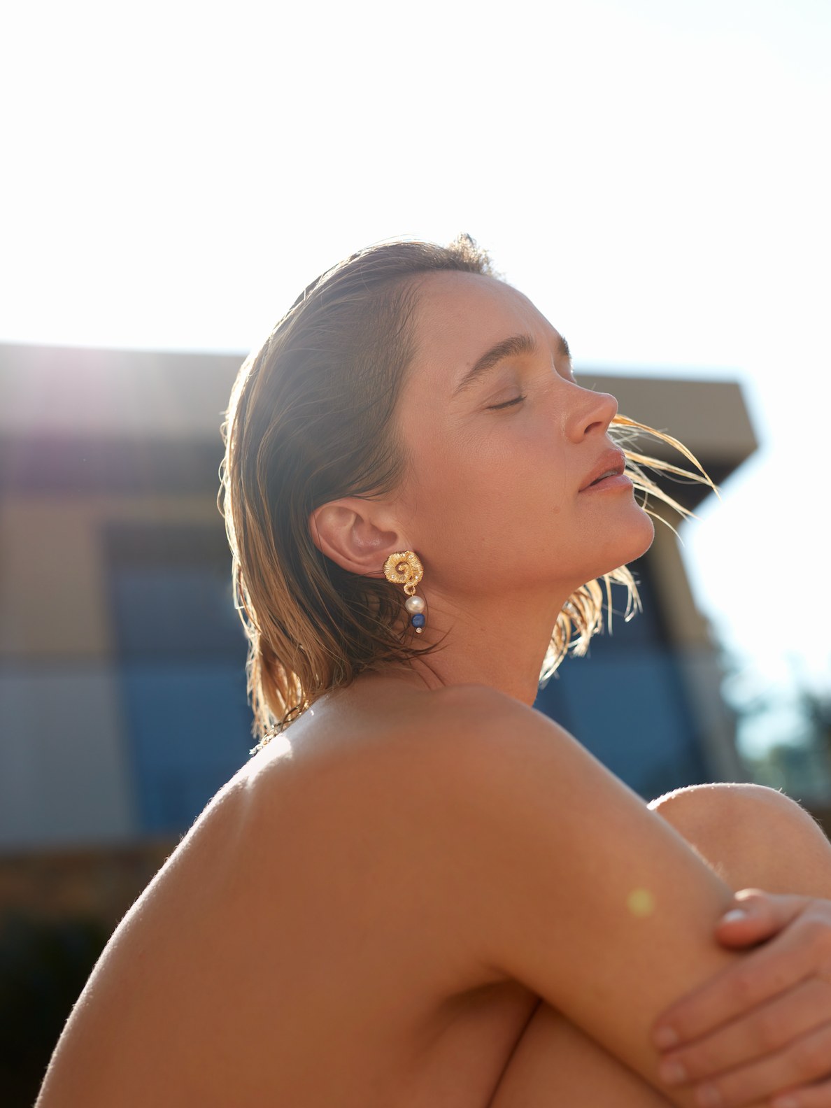 Model in gold and blue ANNI LU earrings beside a pool