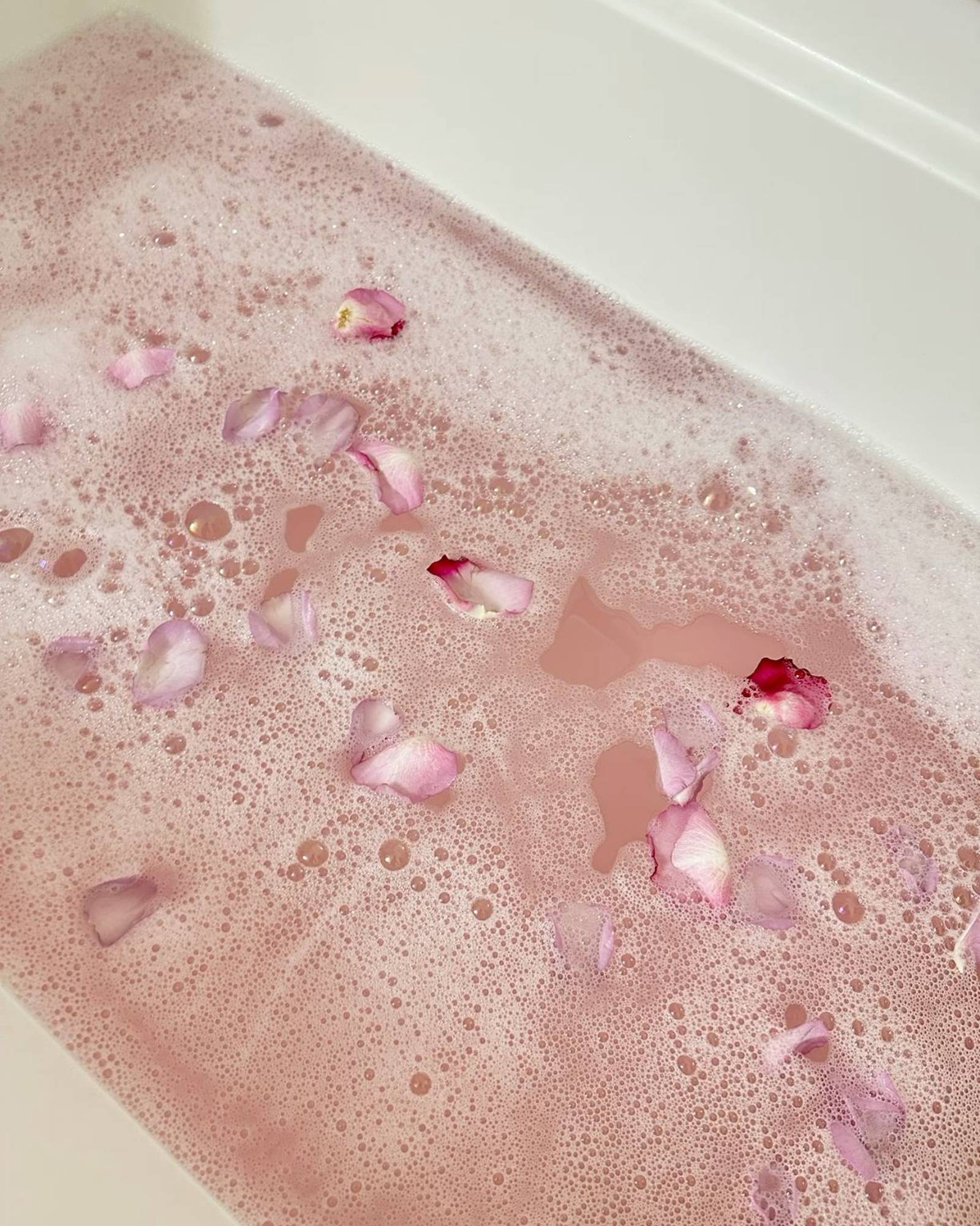 Rose petals floating in pink bath foam