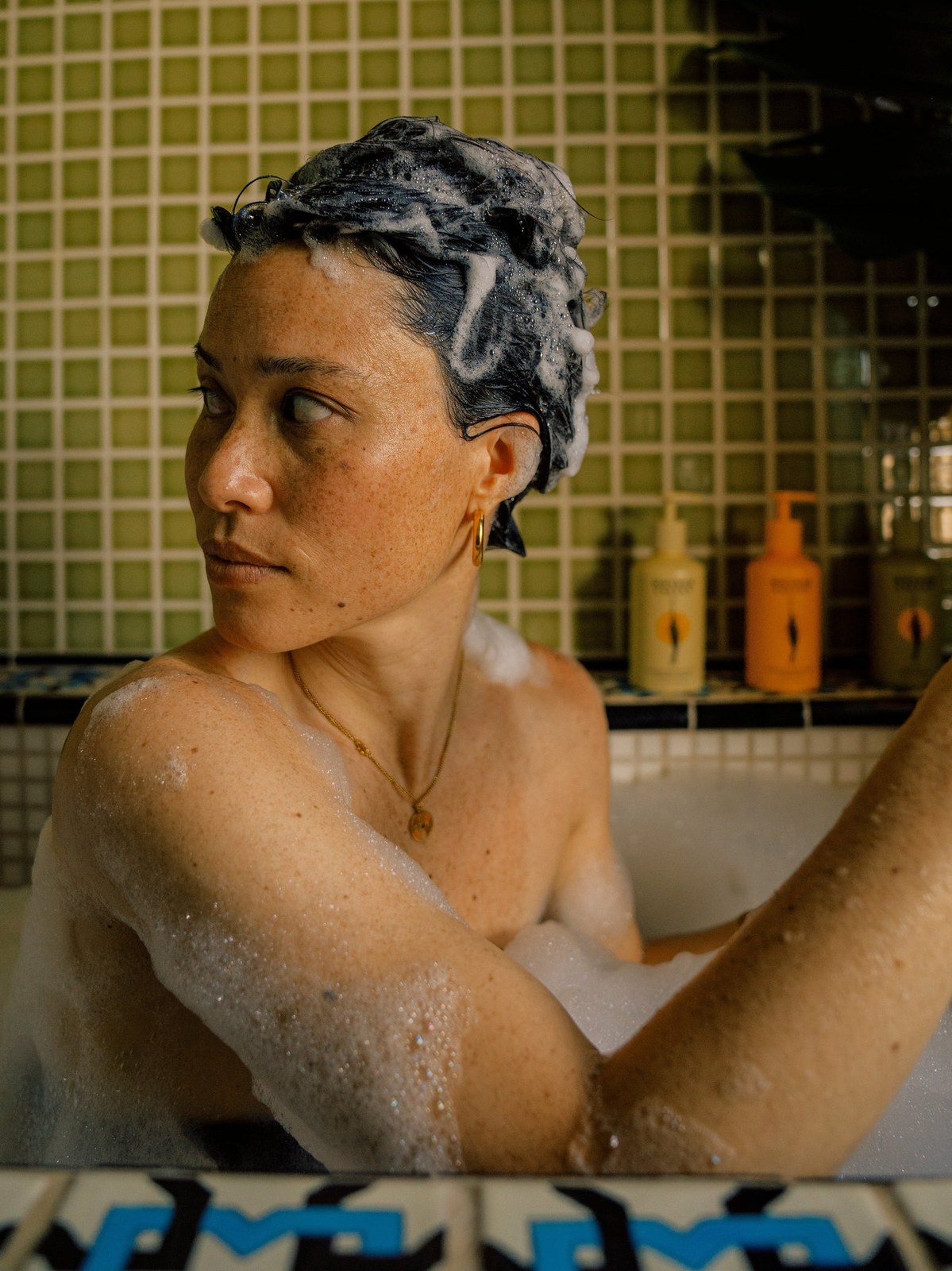 Woman washing her hair in a tiled shower