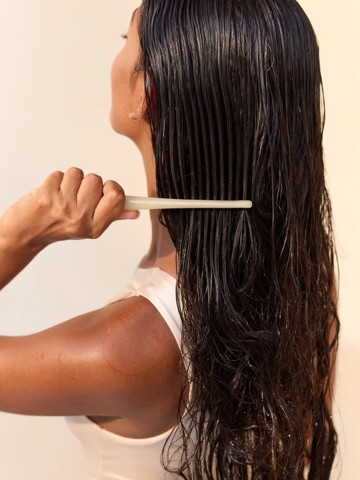 Woman combing long wet dark hair with a wide tooth comb