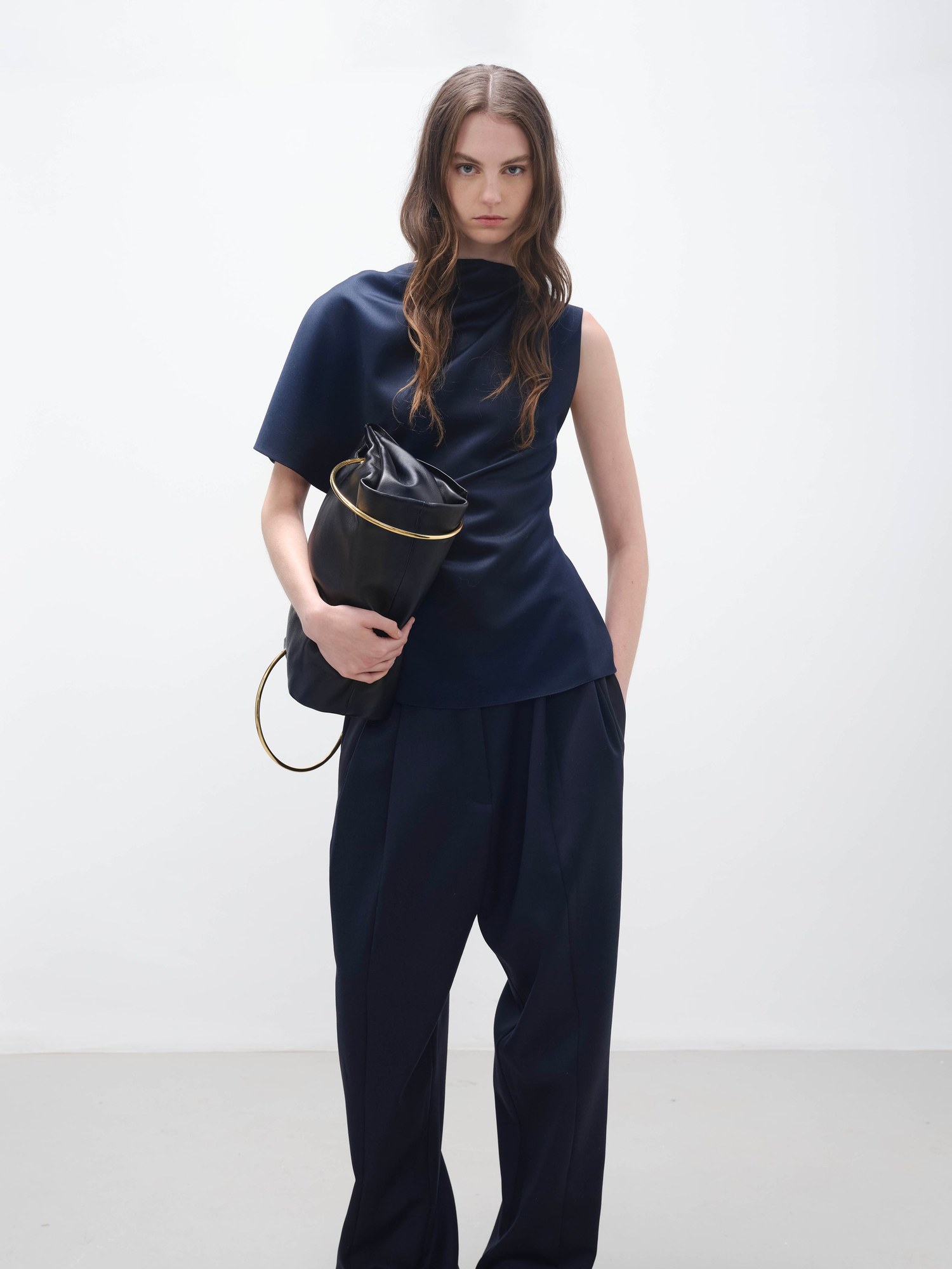 Model in a navy sleeveless top and wide navy trousers with a black bag