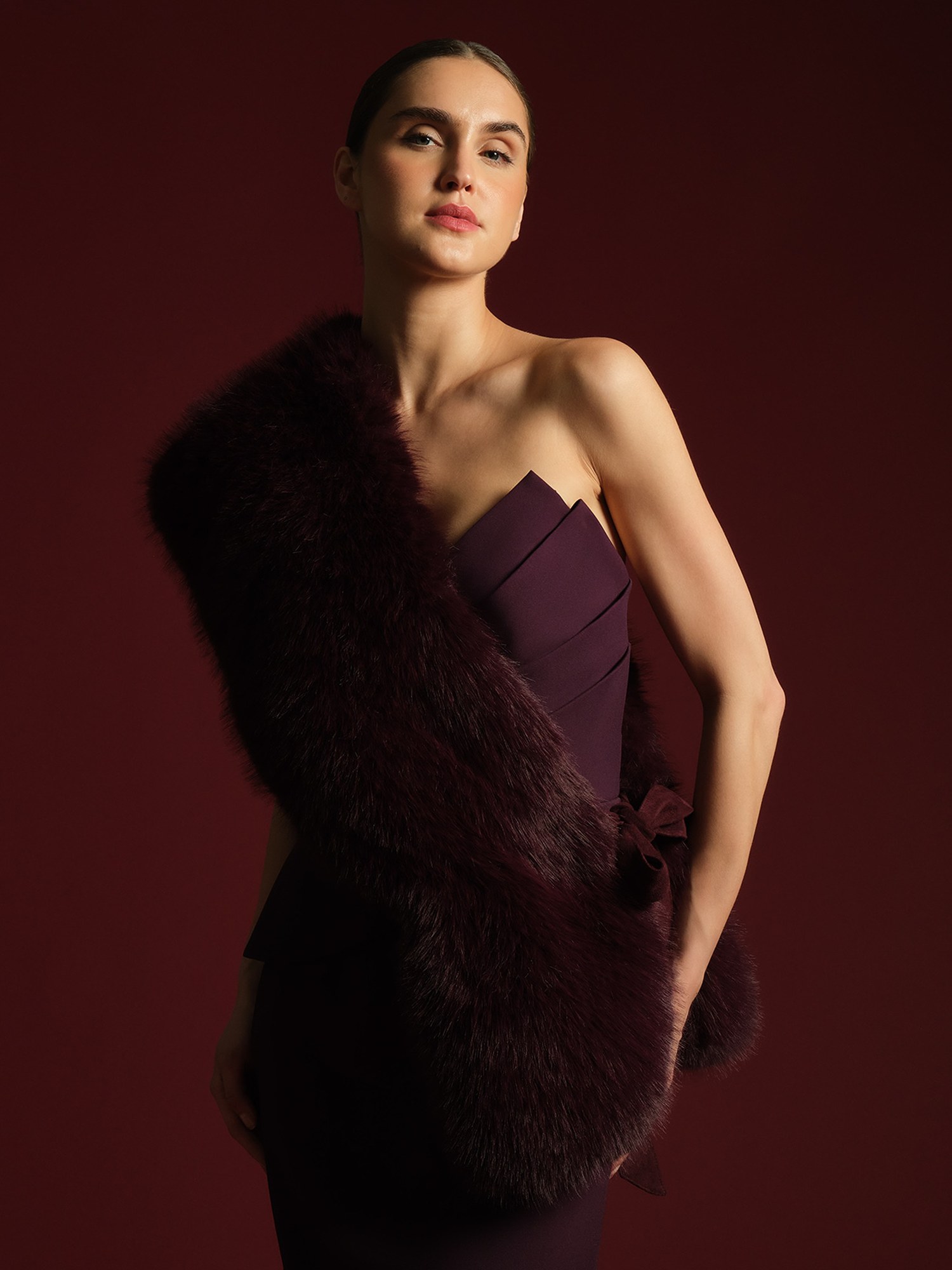 Model in a plum gown wrapped in a faux fur stole