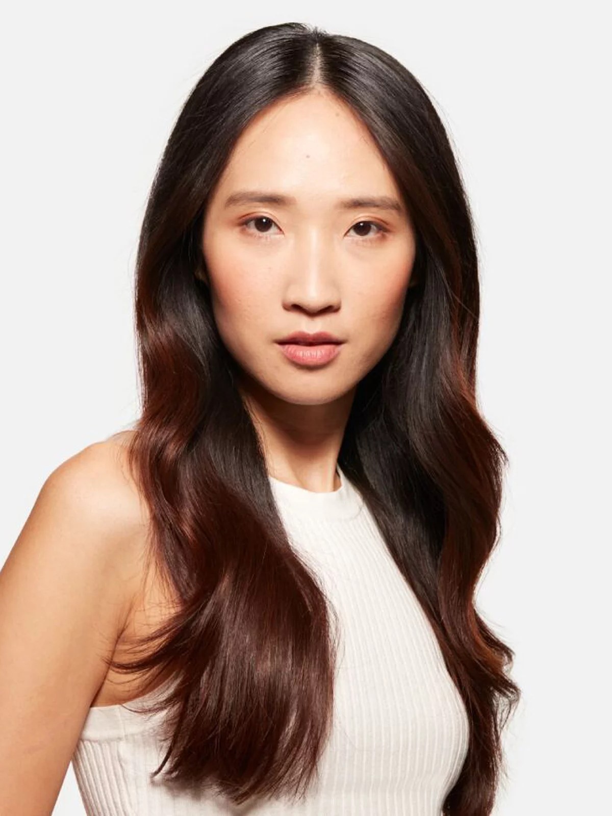 Model with long sleek dark hair in a white halter top