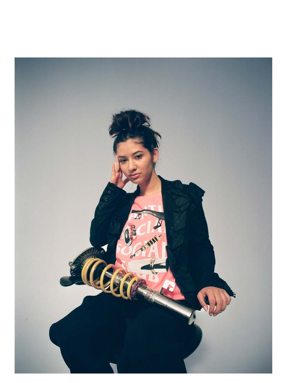 Woman in a dark jacket and graphic tee holding a coiled prop