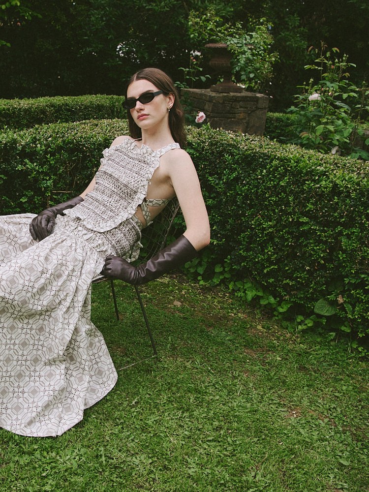 Model wearing a pale textured CLEA dress in a garden setting