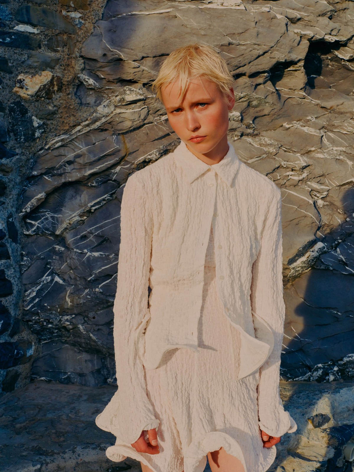 Model in a textured white MSGM blouse against dark stone