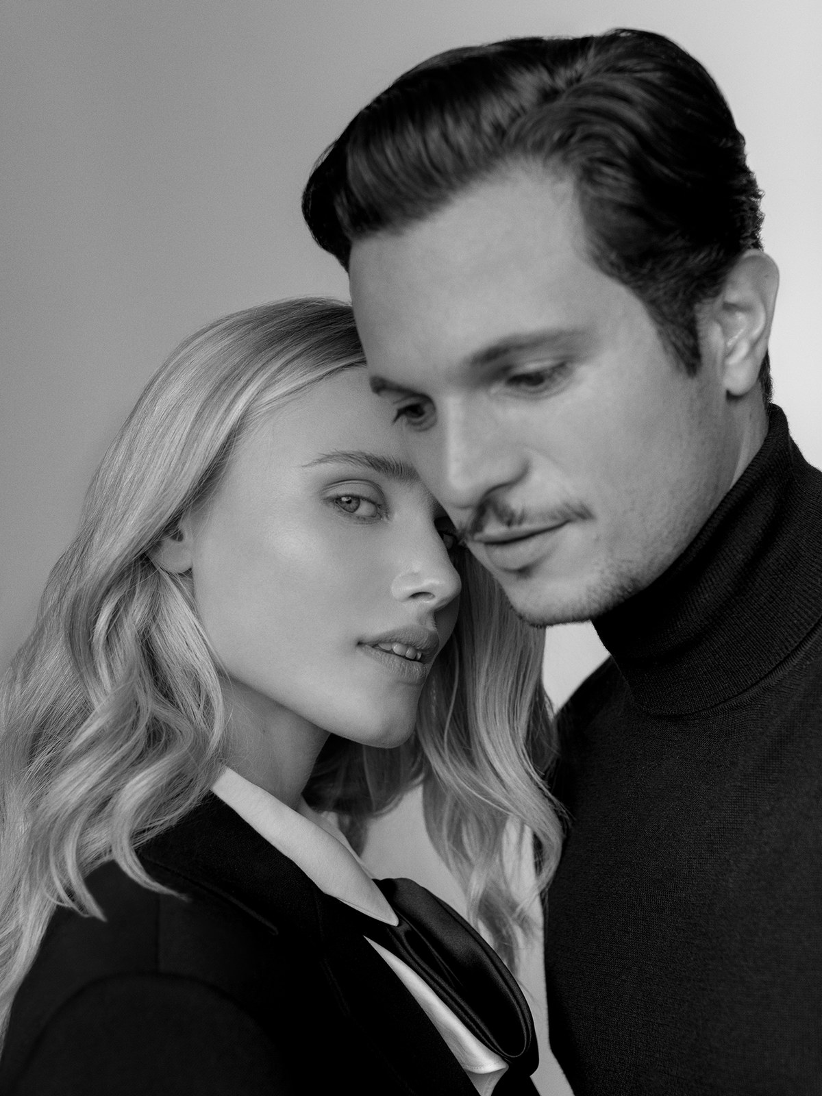 Blonde model and dark-haired man in a close monochrome beauty campaign