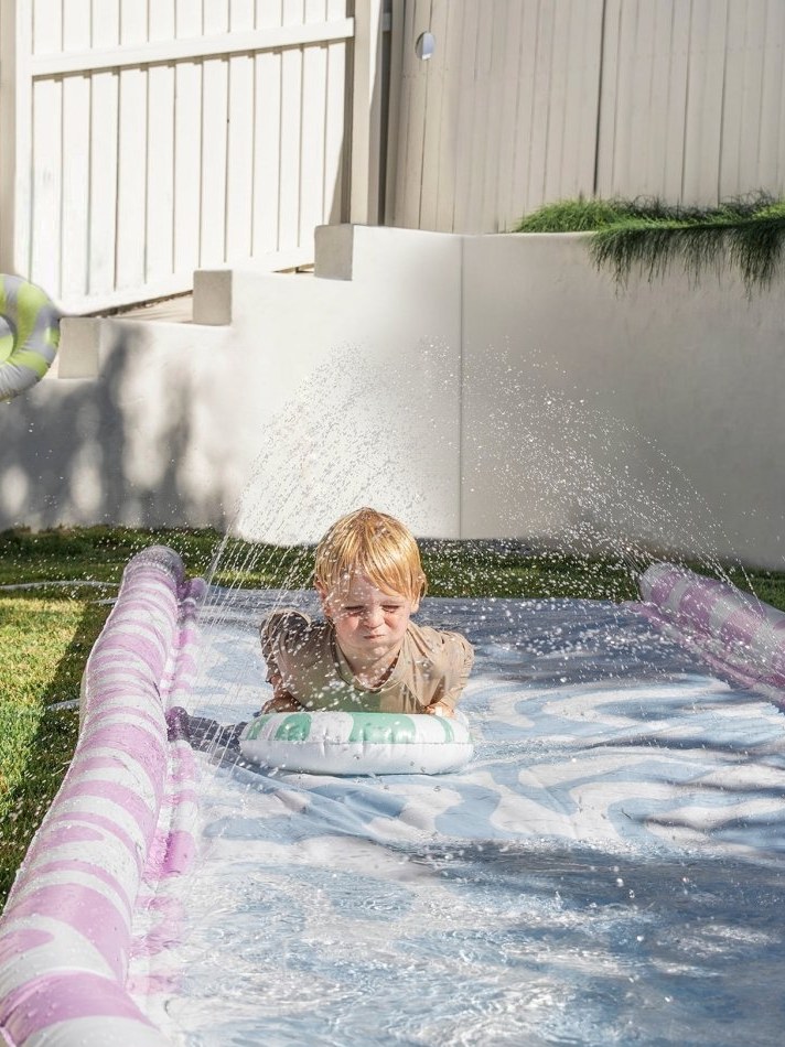 Child playing in a Sunnylife splash pool in a backyard
