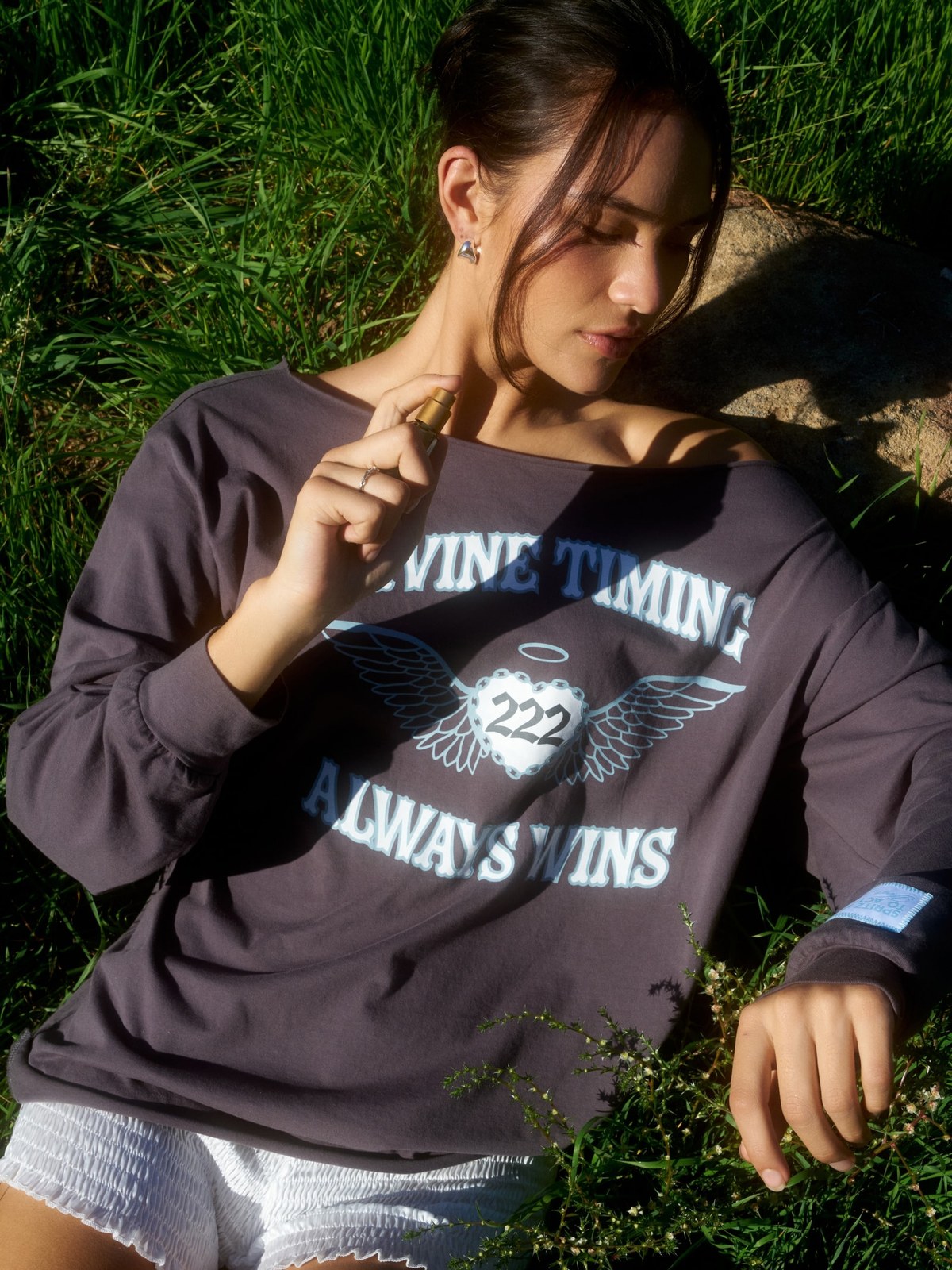 Model lounging in a Divine Timing sweatshirt in a garden