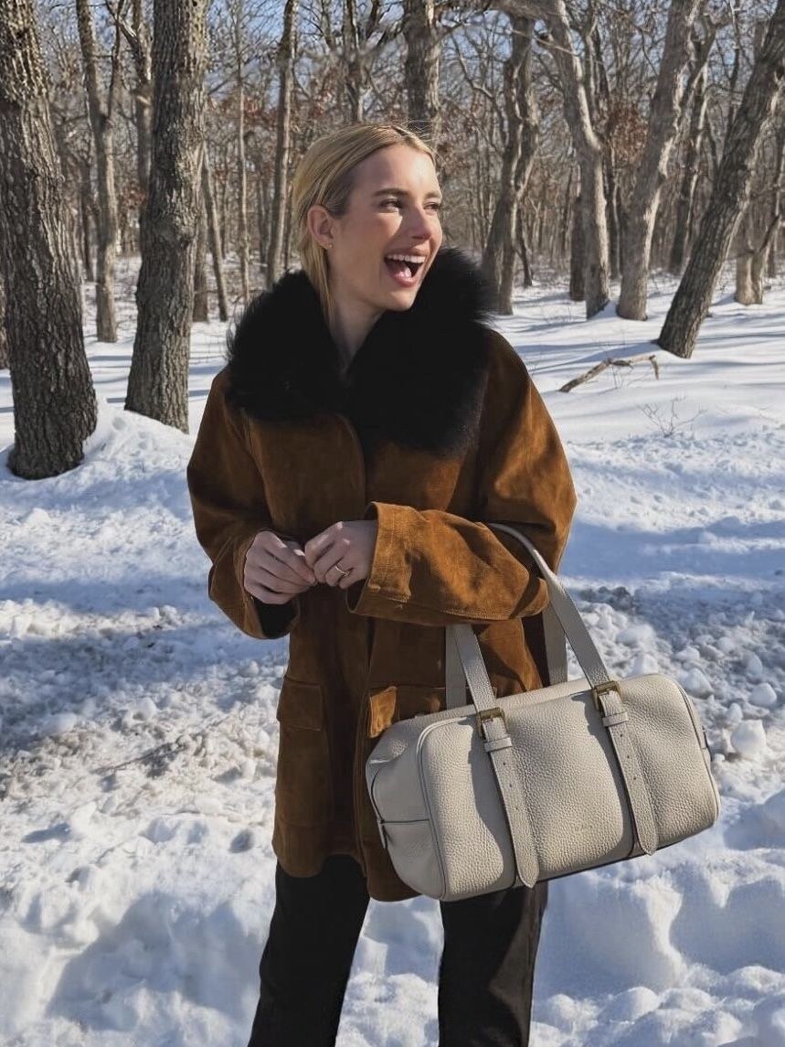 Emma Roberts in a brown shearling coat in a snowy woodland