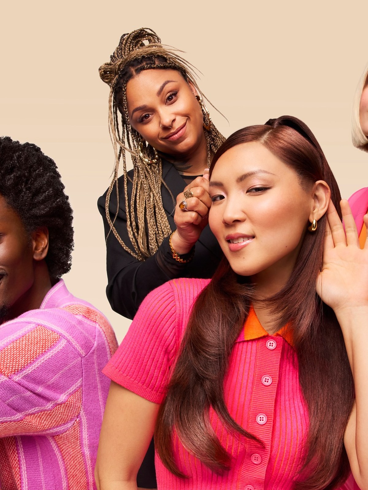 Four people with different hair textures in bright pink and orange outfits on a beige backdrop
