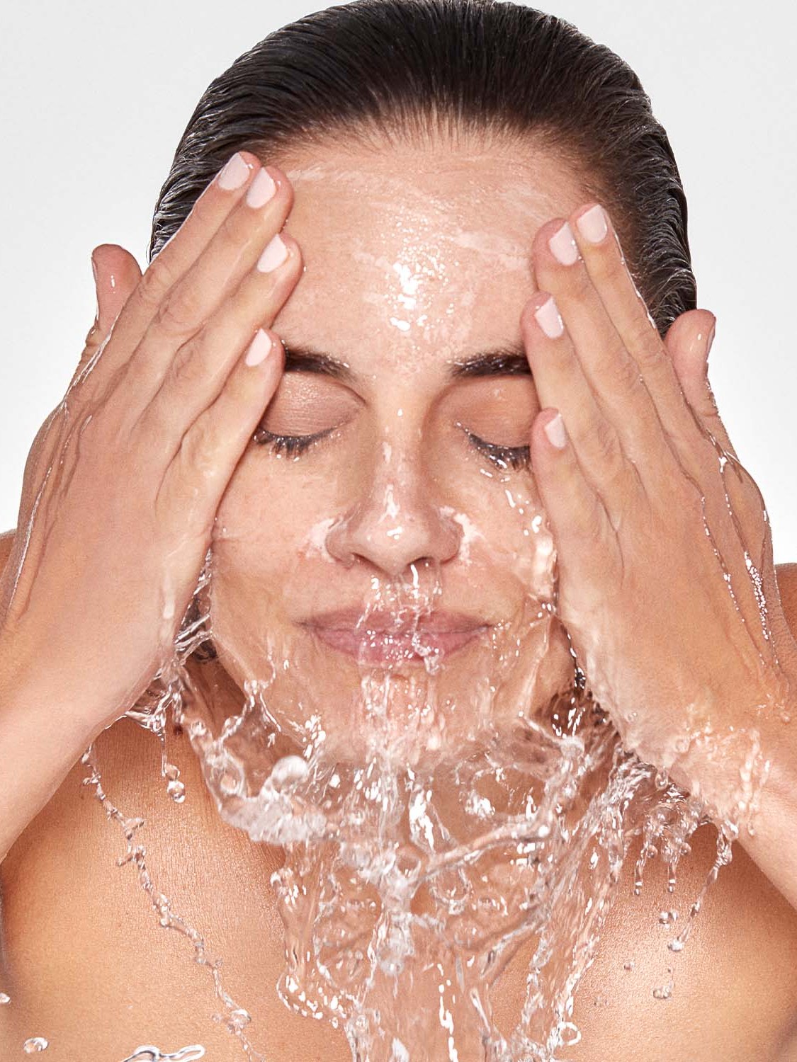 Woman rinsing her face with water in a skincare campaign portrait