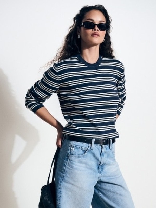 Model in a navy striped sweater and light jeans
