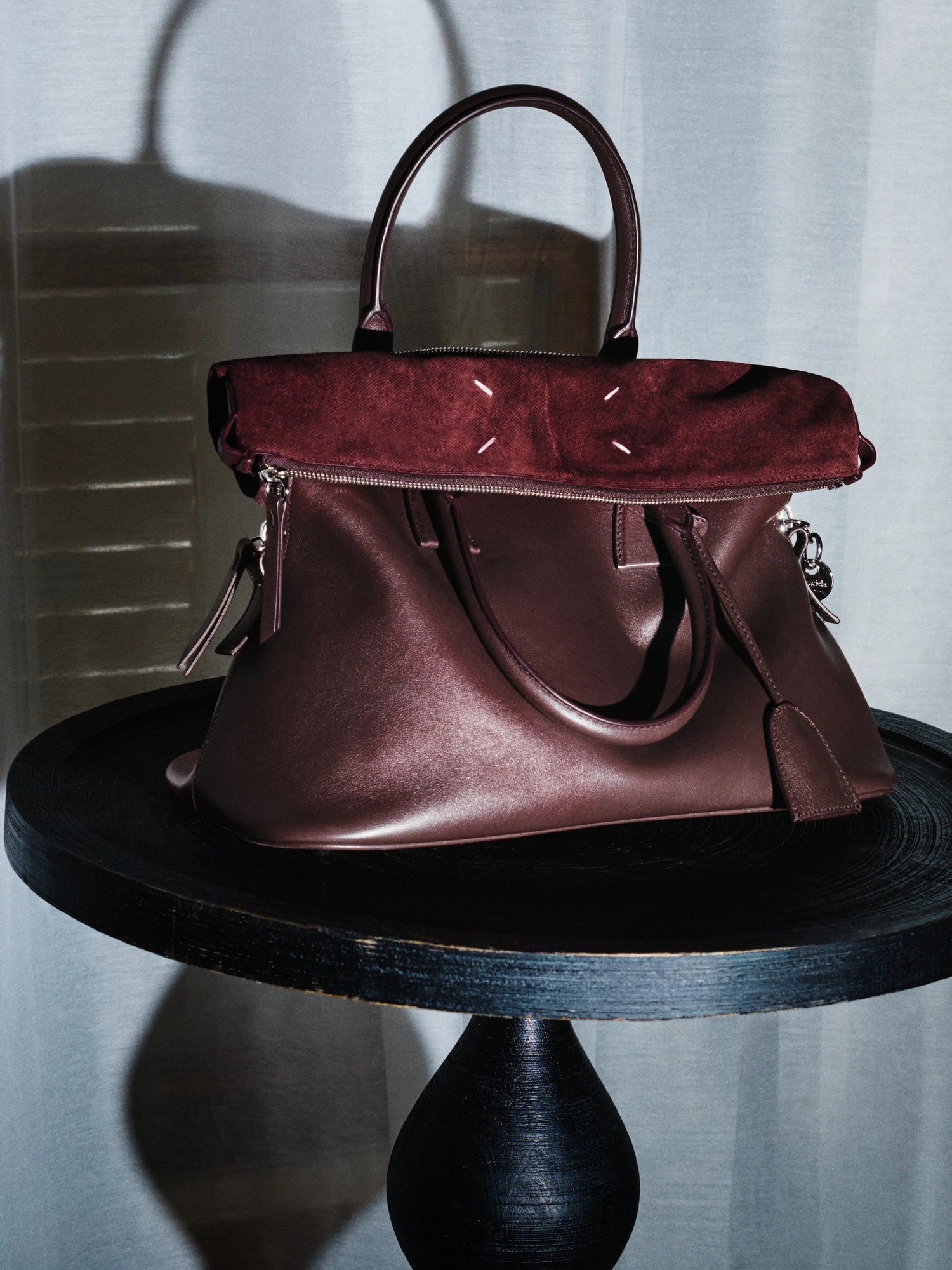 Burgundy leather and suede bag on a black side table