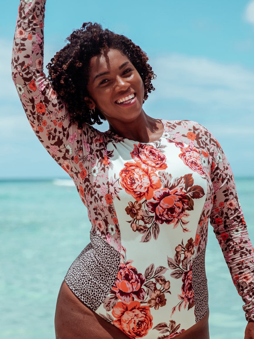 A model in a floral long-sleeved swimsuit standing in shallow water