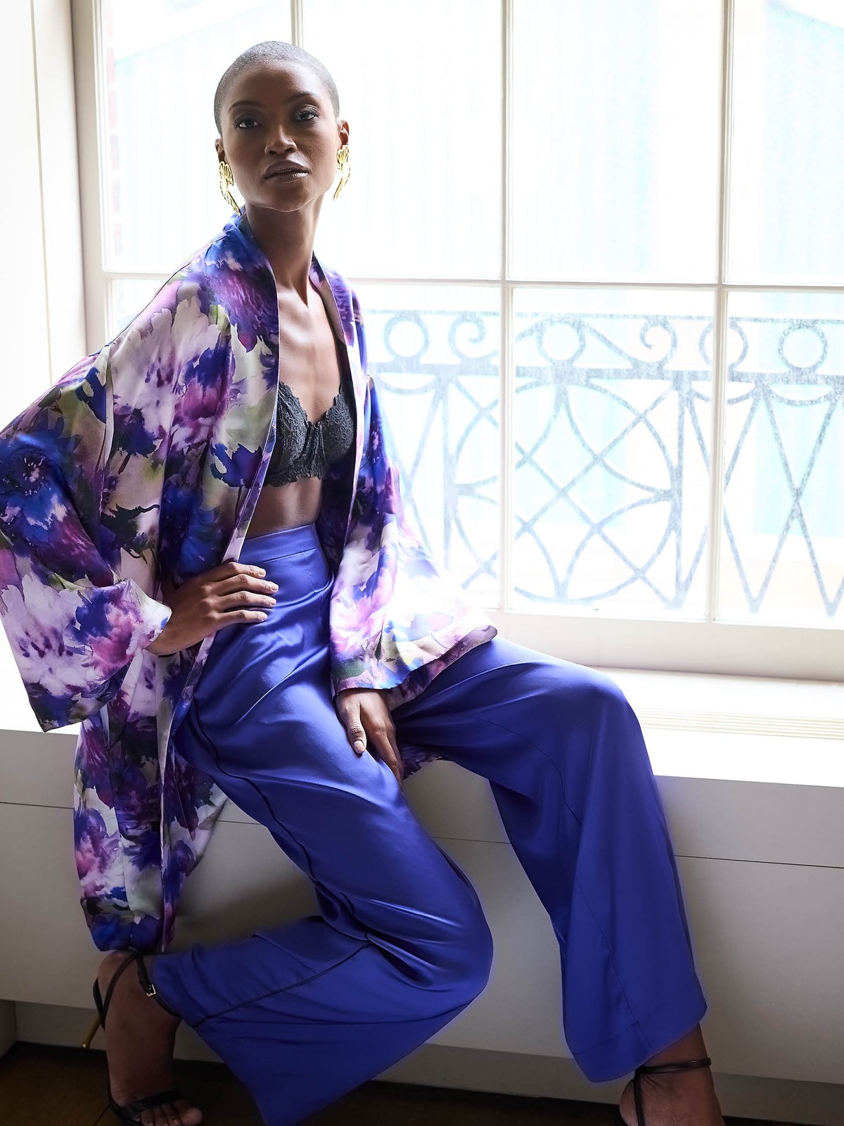 Model in a floral kimono and cobalt trousers seated by a window