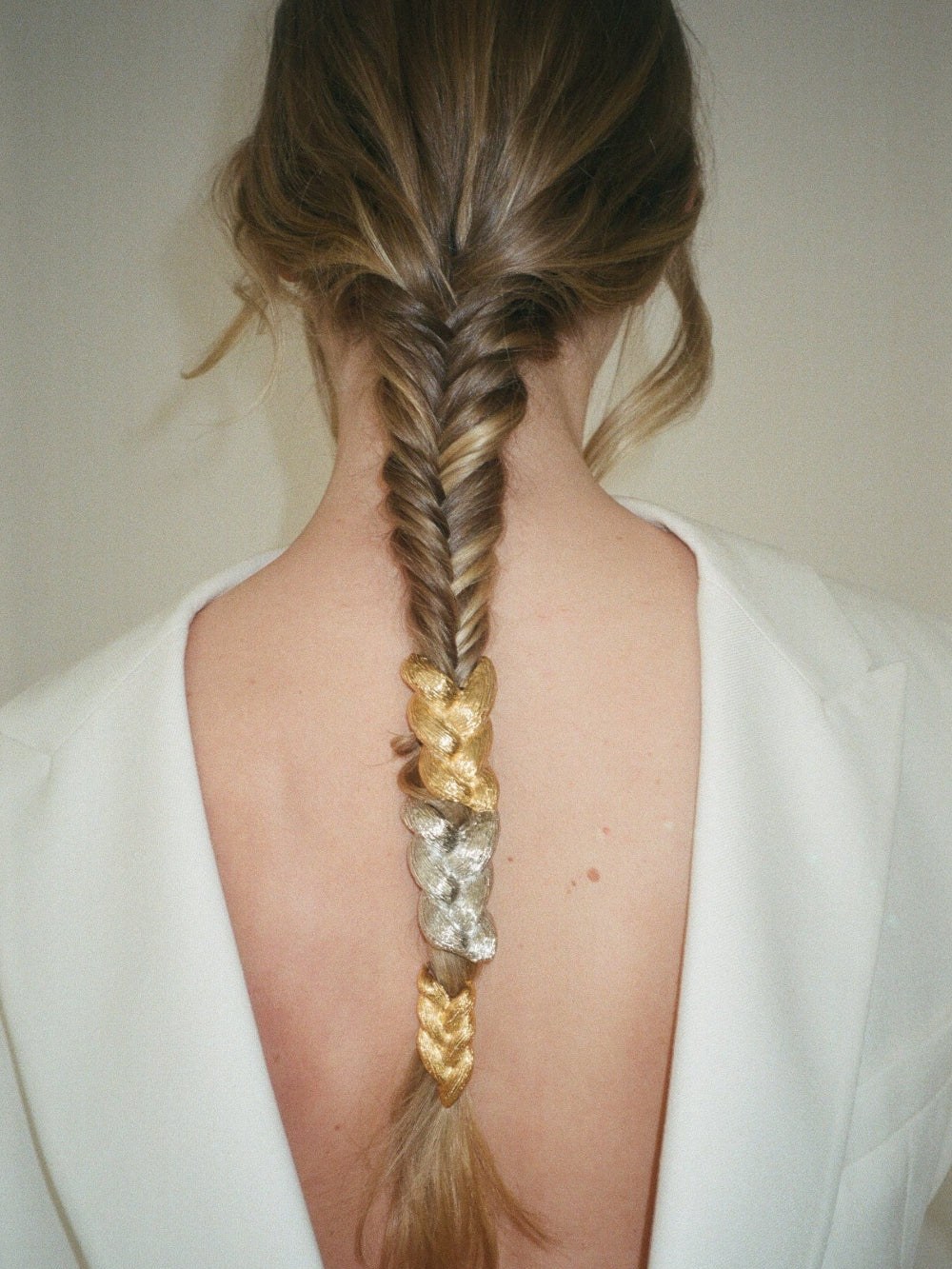 Gold hair cuff threaded through a long braid, photographed from behind