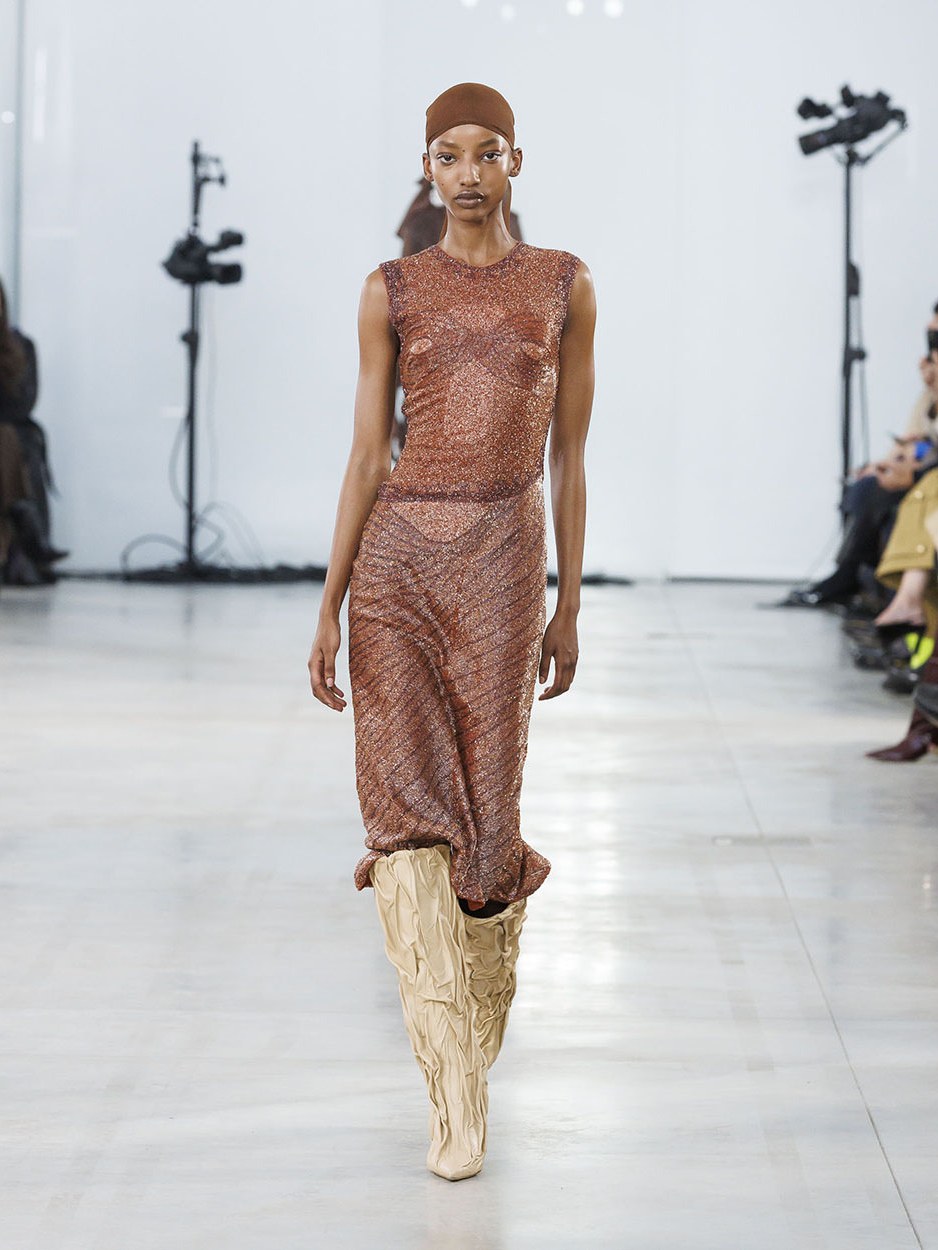 Model in a brown textured dress walking the Fall Winter 2025 runway