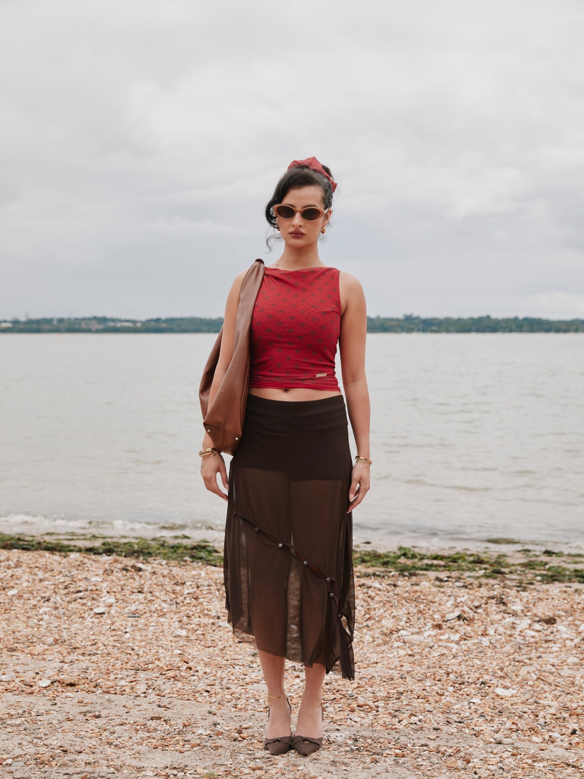Model in a red House of Sunny polka-dot top and sheer skirt by the water