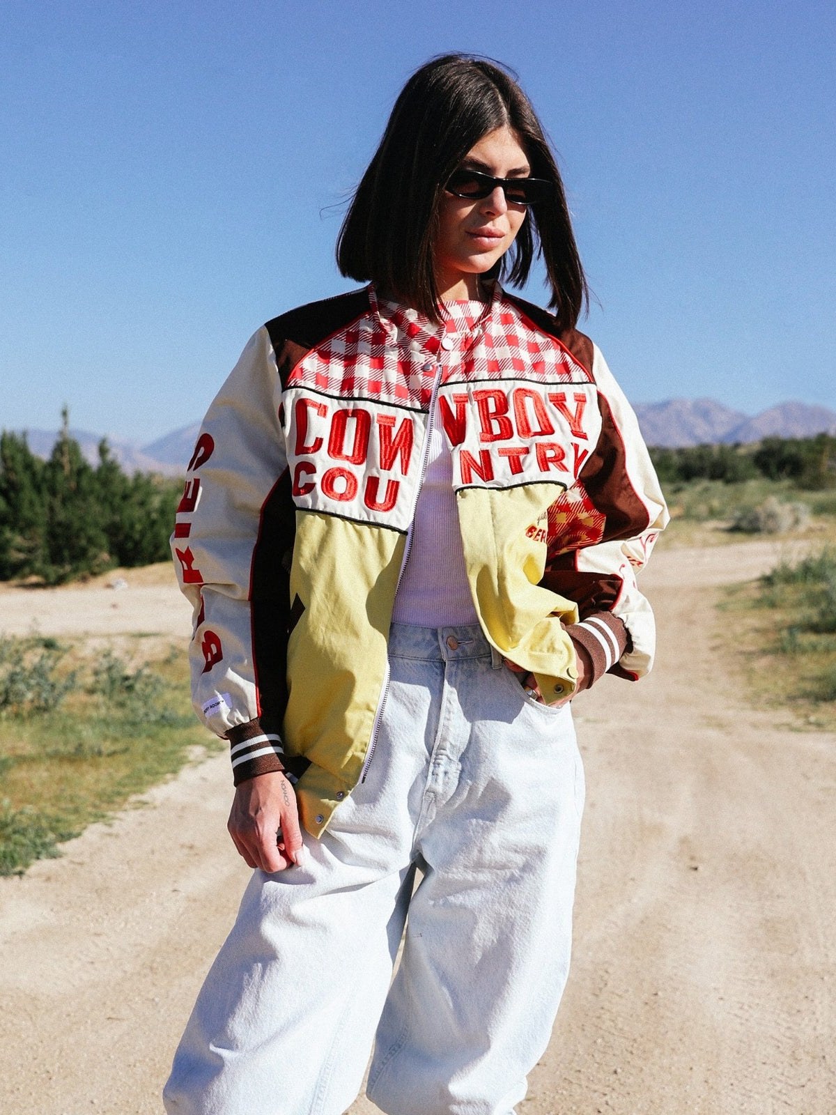Model in a red gingham racing jacket on a sunlit desert road