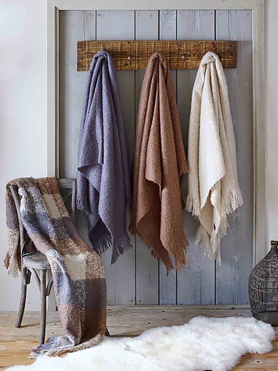 Neutral throws hang beside a chair and layered rug