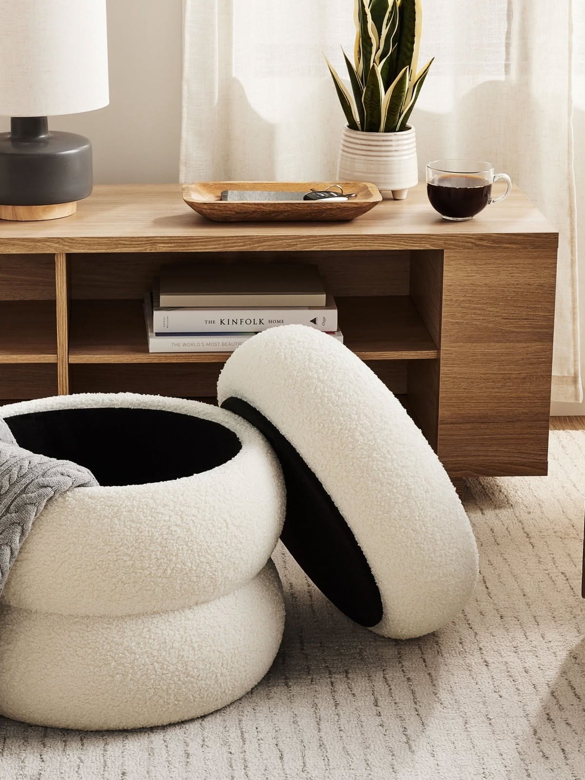 Round cream tiered ottoman in front of a wooden sideboard