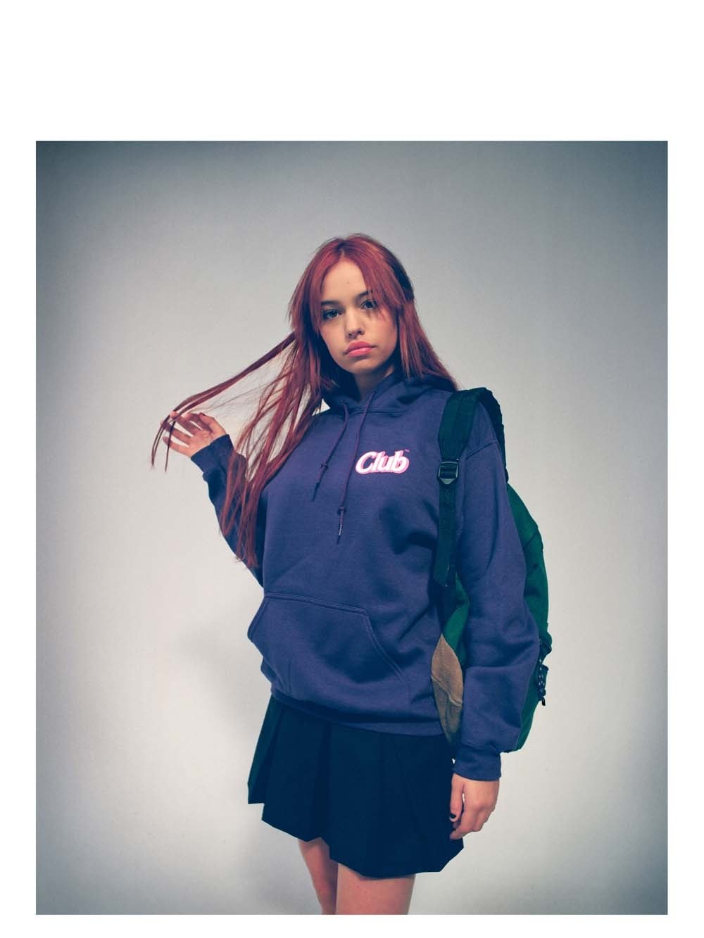 Woman in a navy hoodie and black skirt in a studio