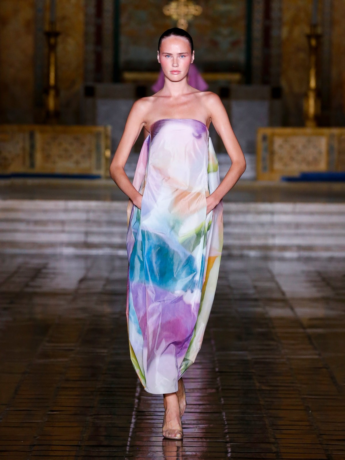 A model wears a softly colored printed dress on the Spring Summer 2026 runway.