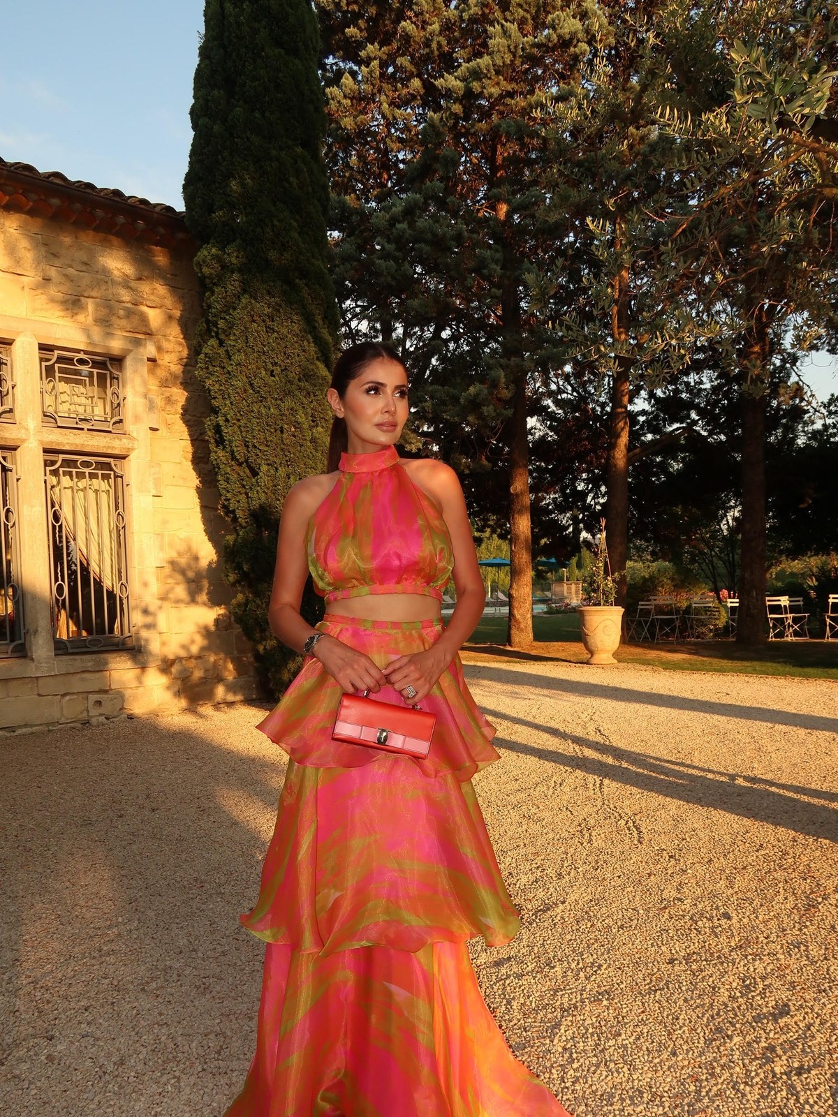 Model in a pink and green printed dress by a stone building