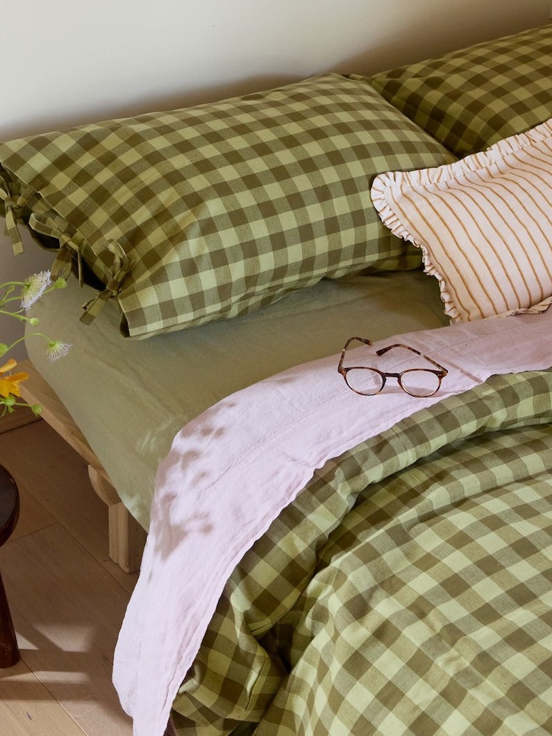 Green checked bedding and pillows in a wood-paneled cabin bedroom