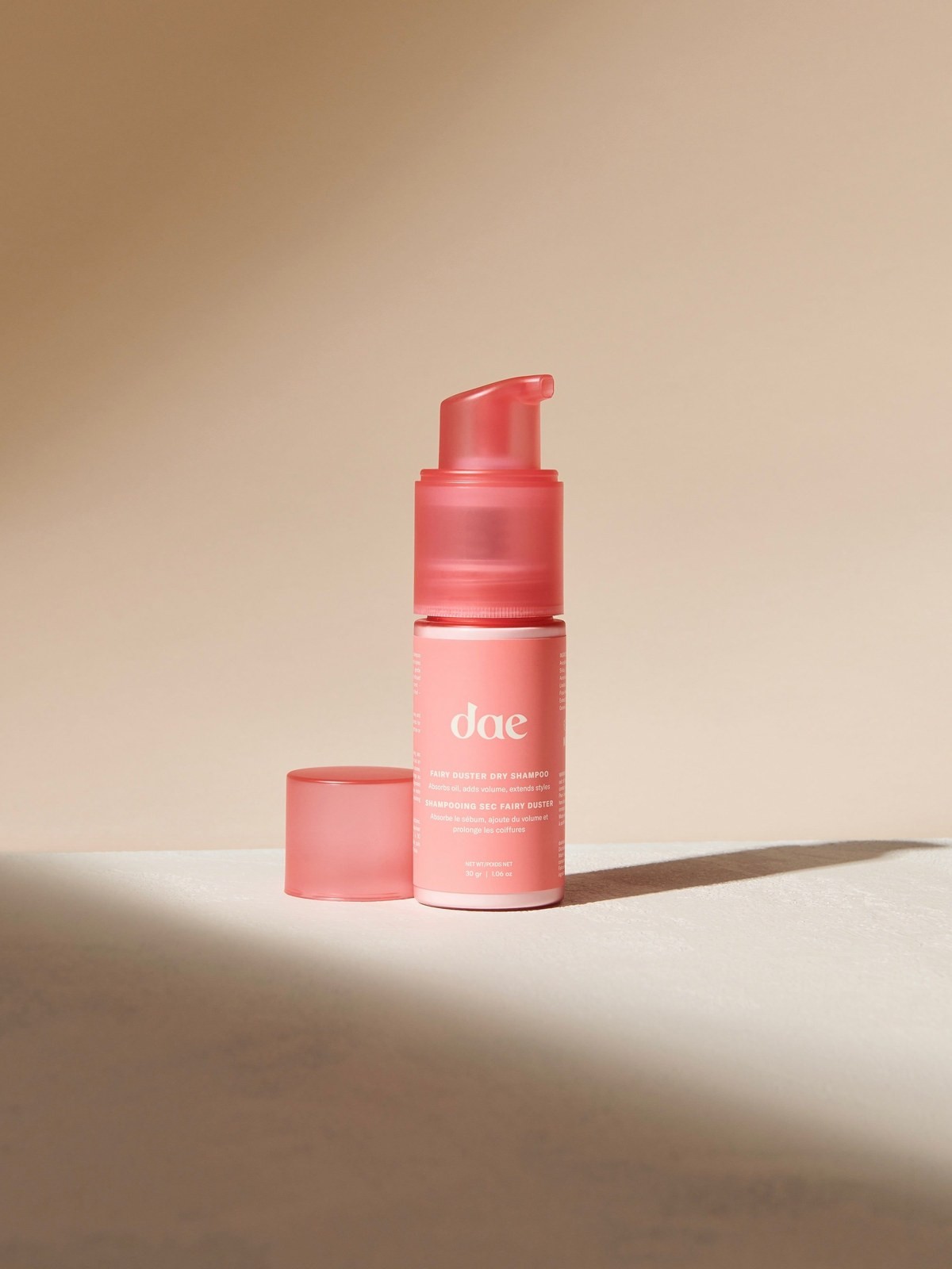 Pink dae Fairy Duster dry shampoo powder pump bottle on a beige background