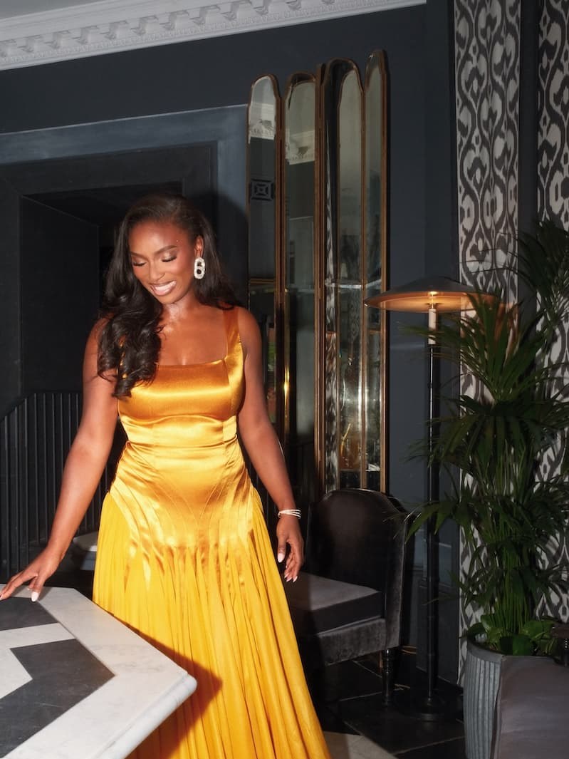 Woman wearing a gold satin gown in a dark interior