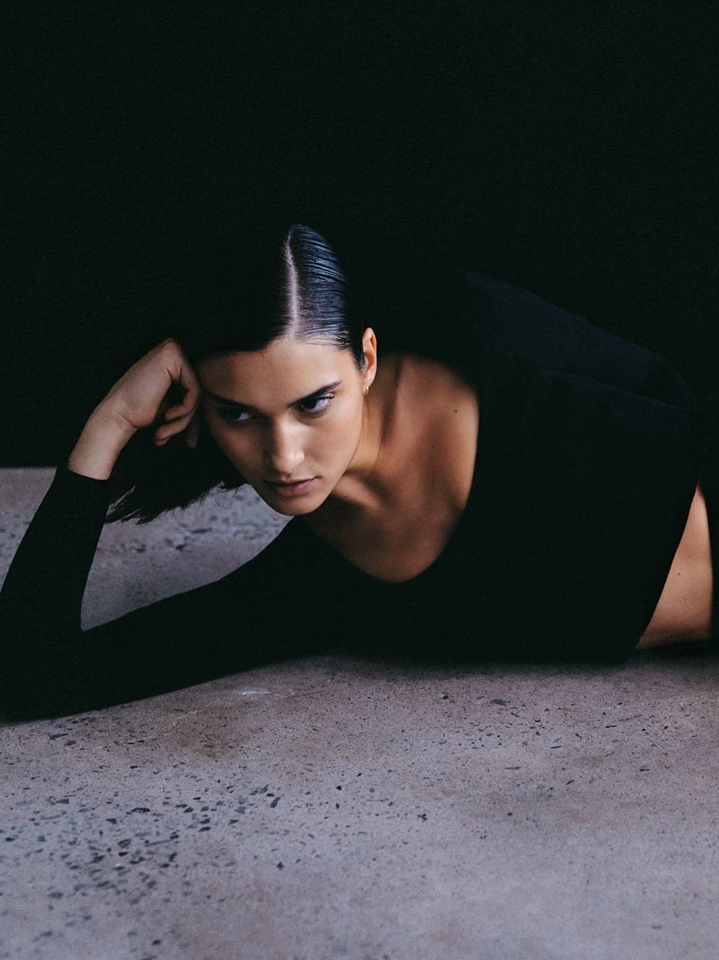 Model in black knit separates reclining on a studio floor
