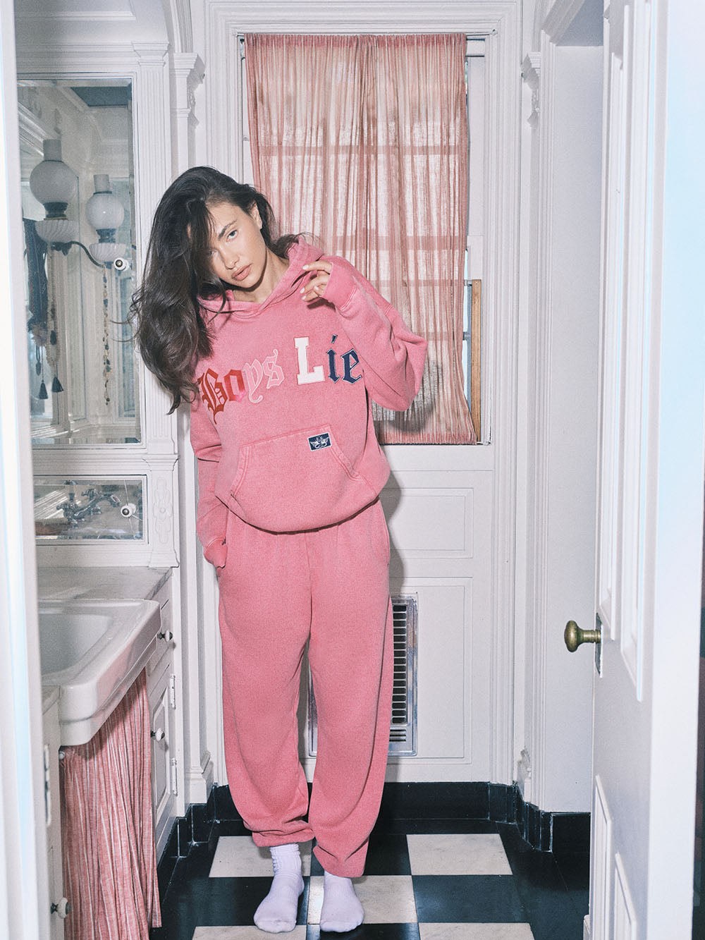 Model in a pink graphic sweatsuit in a tiled room