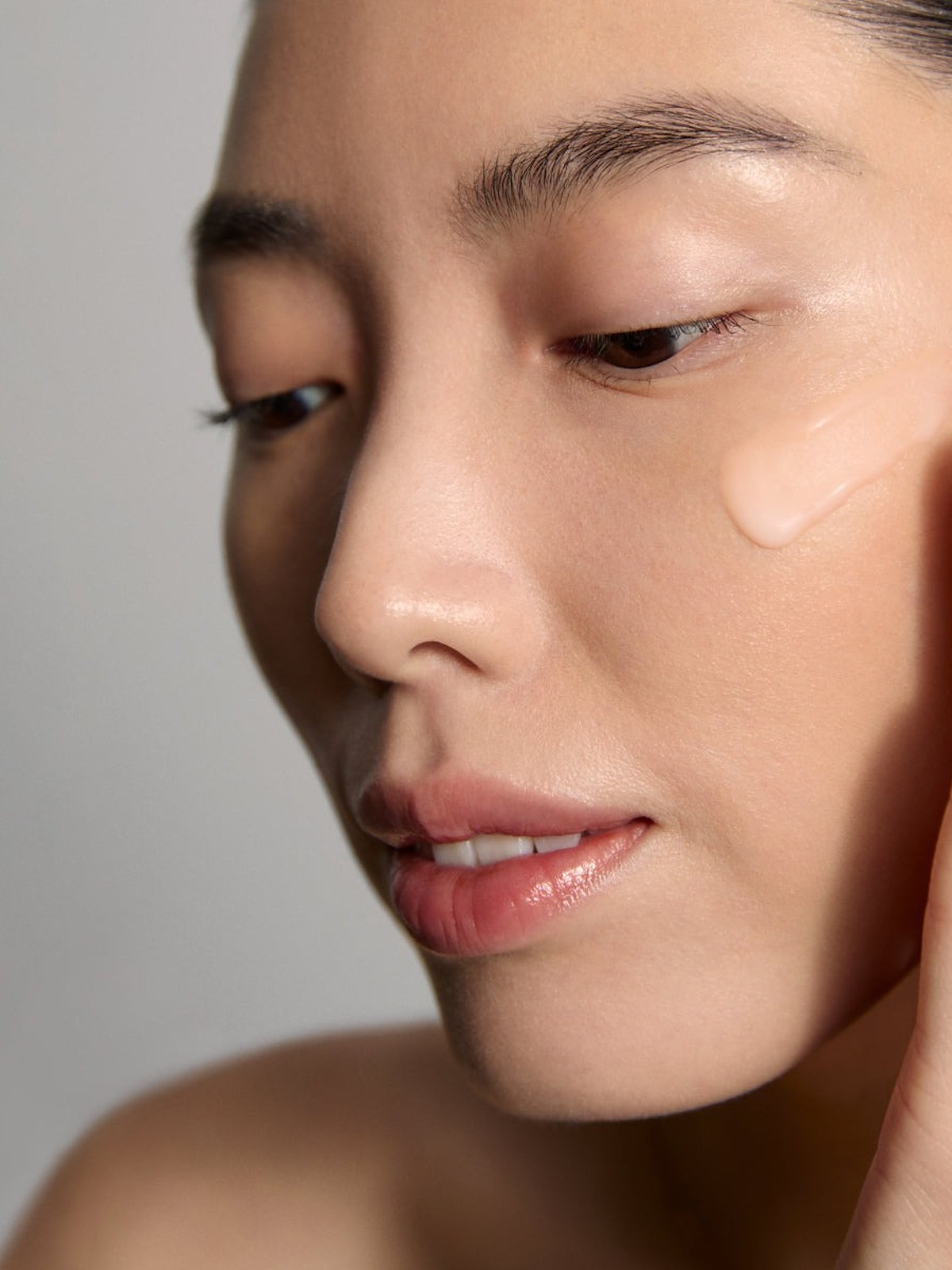 Model with a dab of cream on her cheek and a hand at her face