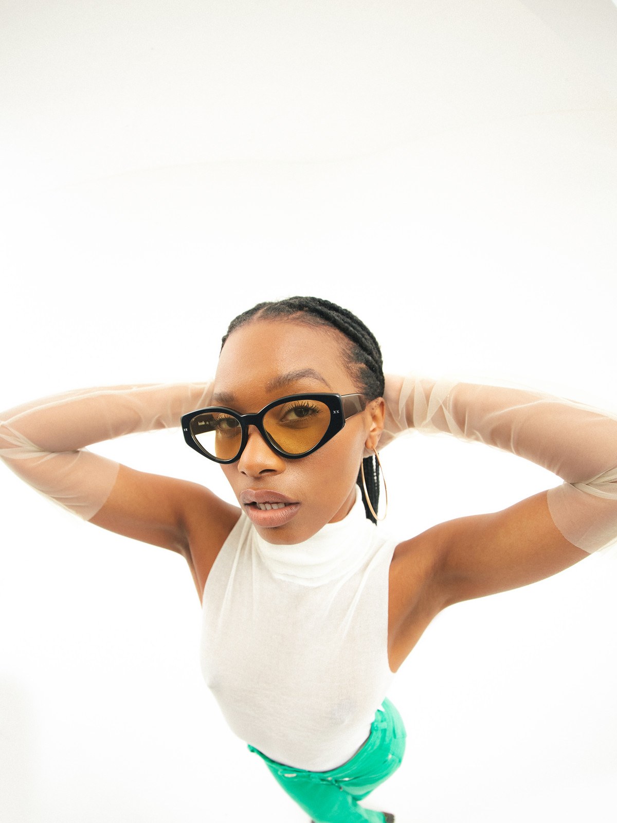 Model in yellow-tinted Lexxola sunglasses with a white top and green skirt