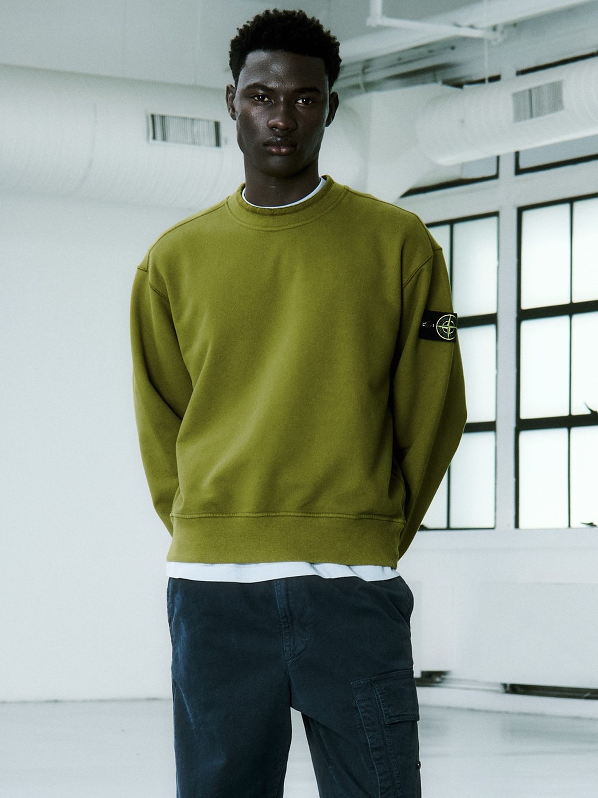Model in an olive fleece sweatshirt and navy cargo trousers