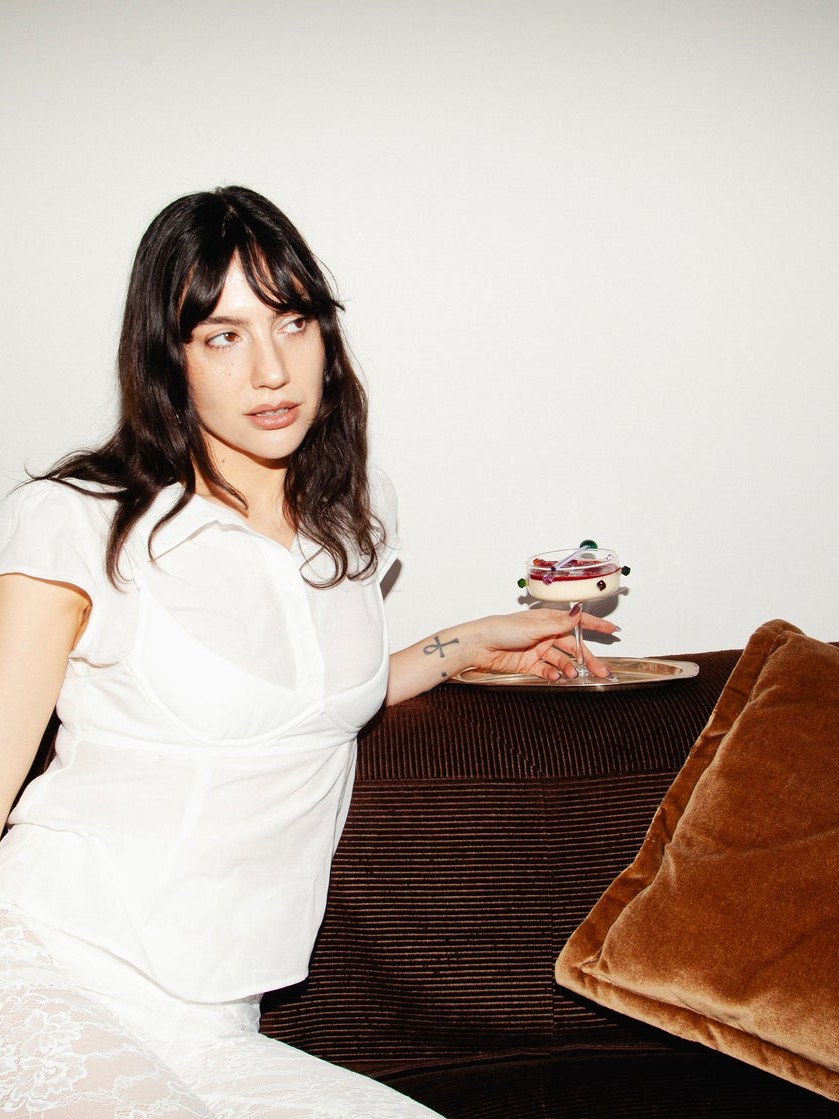 Brooke Holiday on a brown sofa holding a coupe glass