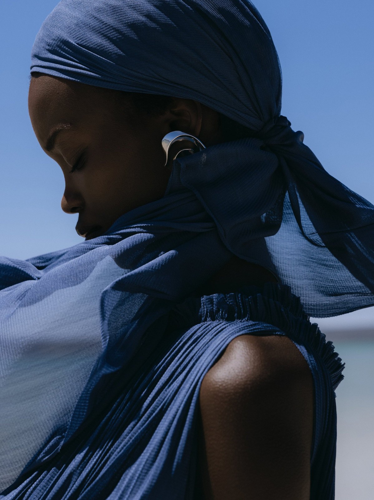 Close profile of a model in deep blue Hanne Bloch fabric against the sky