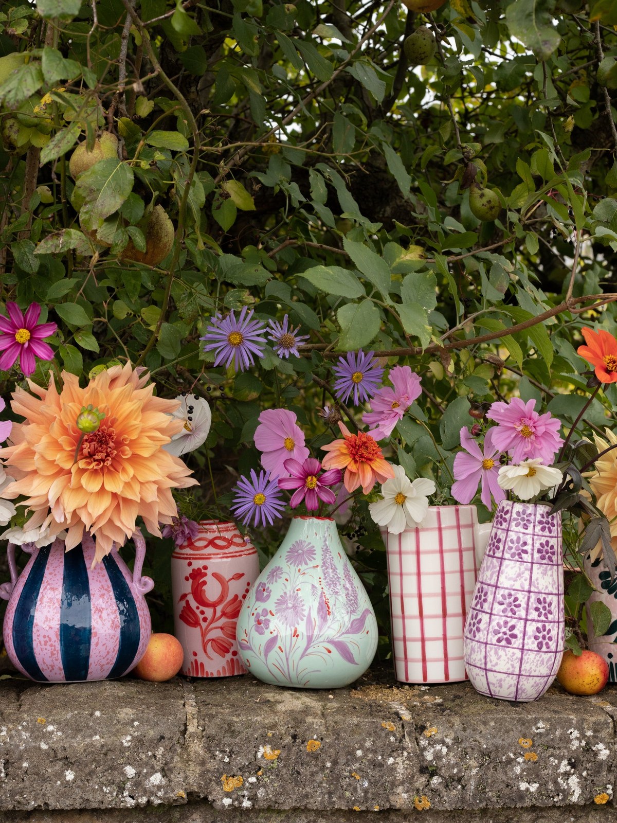 Colorful ceramic vases arranged on a garden stone wall